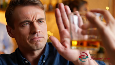 Мужчина отодвигает от себя рукой стакан с алкоголем